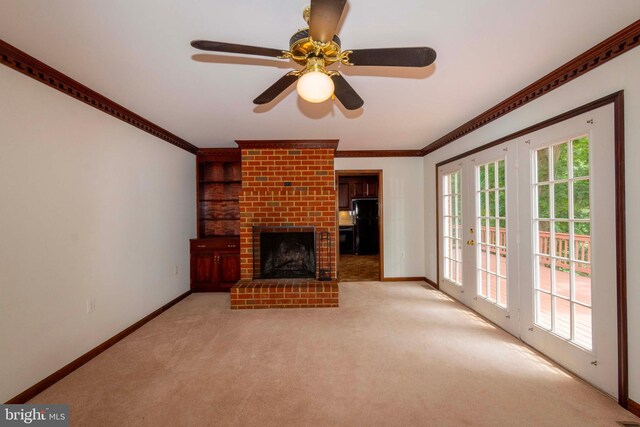 unfurnished living room featuring light carpet, french doors, a fireplace, ceiling fan, and crown molding