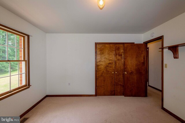 unfurnished bedroom featuring a closet and light colored carpet