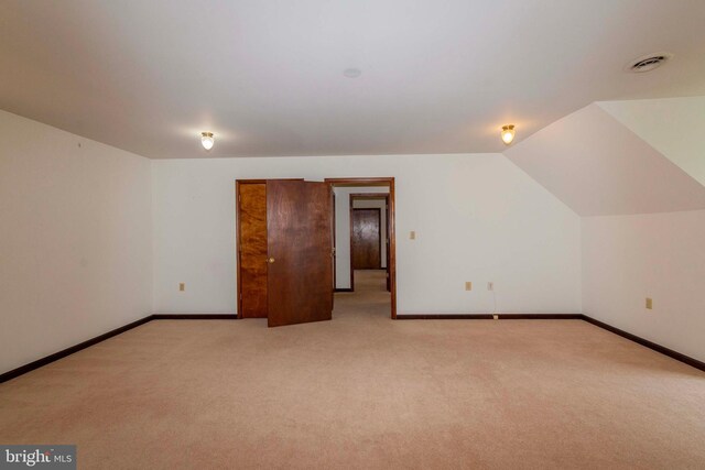 additional living space featuring light colored carpet and vaulted ceiling