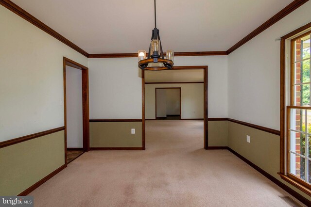 carpeted spare room with a notable chandelier and ornamental molding