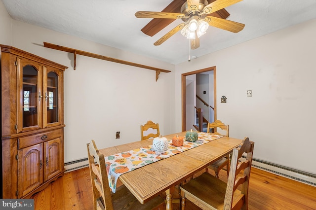 dining room featuring ceiling fan, light wood-type flooring, and a baseboard heating unit