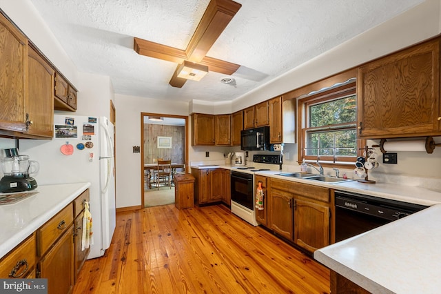 kitchen with sink, light hardwood / wood-style flooring, black appliances, and a textured ceiling