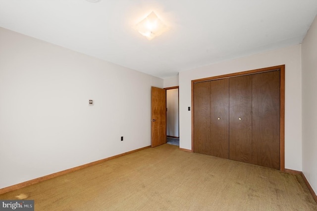 unfurnished bedroom featuring light carpet and a closet