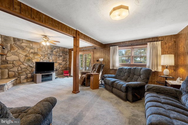 living room featuring ceiling fan, a textured ceiling, light carpet, and wood walls