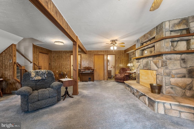 carpeted living room featuring ceiling fan, a textured ceiling, and wood walls