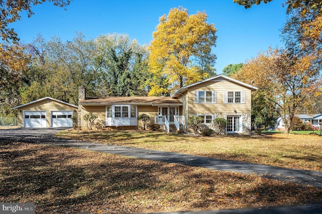 tri-level home with a garage, an outdoor structure, and a front yard