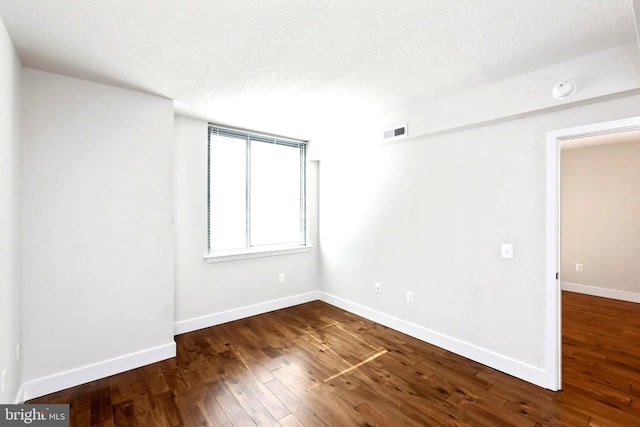 spare room featuring dark hardwood / wood-style floors and a textured ceiling