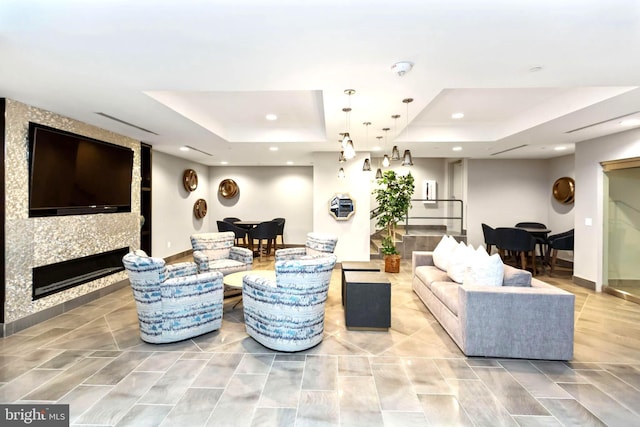 living room featuring a tray ceiling and a large fireplace