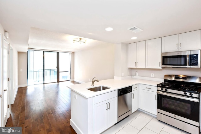 kitchen with kitchen peninsula, stainless steel appliances, white cabinetry, and sink