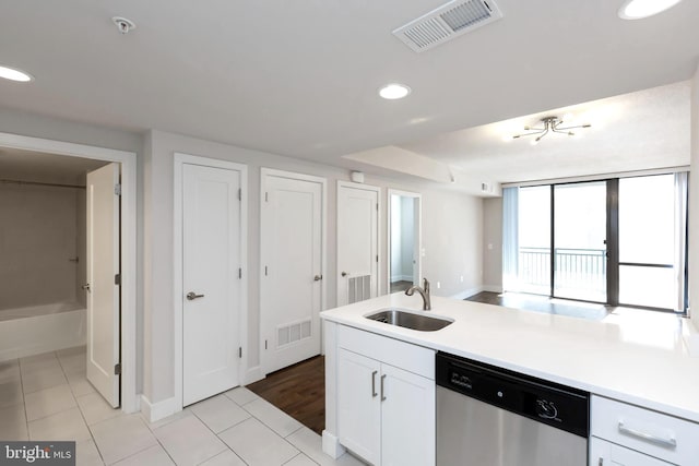 kitchen featuring stainless steel dishwasher, white cabinetry, sink, and light tile patterned floors