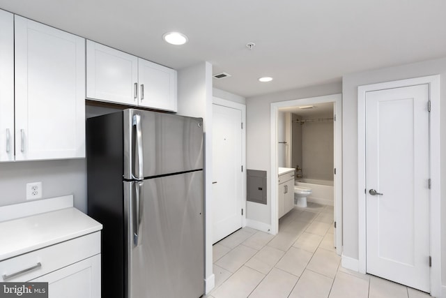 kitchen featuring stainless steel refrigerator, white cabinets, and light tile patterned flooring