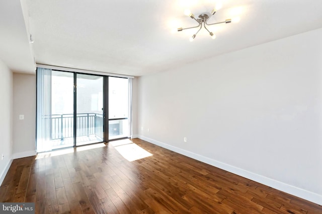 spare room featuring hardwood / wood-style floors, a wall of windows, and an inviting chandelier