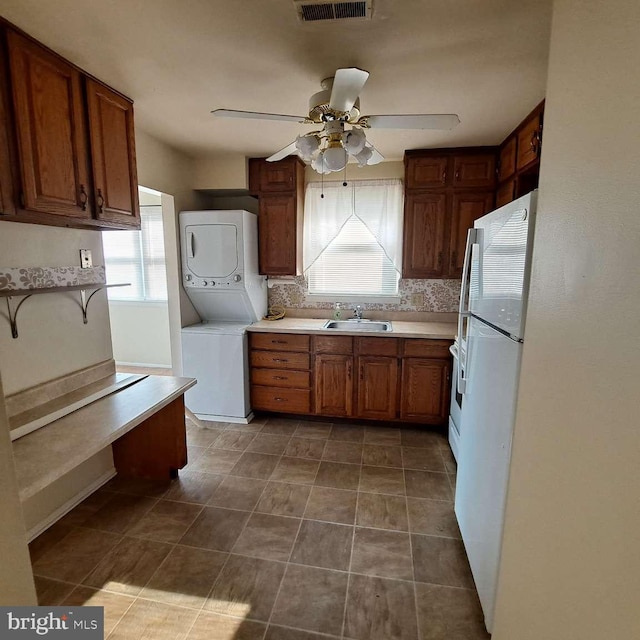 kitchen featuring stacked washer / dryer, a healthy amount of sunlight, and dark tile floors