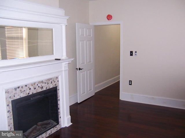 unfurnished living room featuring dark wood-type flooring and a tile fireplace