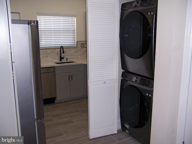 clothes washing area featuring stacked washer / dryer and sink