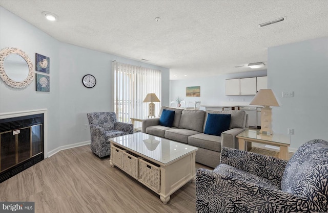 living room featuring a textured ceiling and light wood-type flooring