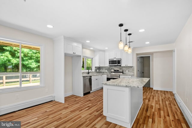 kitchen with pendant lighting, white cabinets, stainless steel appliances, and a baseboard heating unit