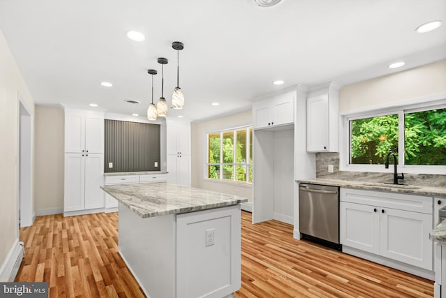 kitchen featuring sink, a kitchen island, stainless steel dishwasher, decorative light fixtures, and white cabinets