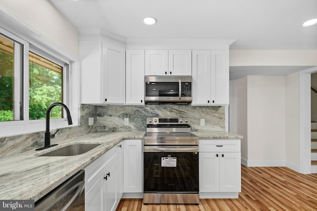 kitchen featuring light stone counters, sink, white cabinets, and appliances with stainless steel finishes