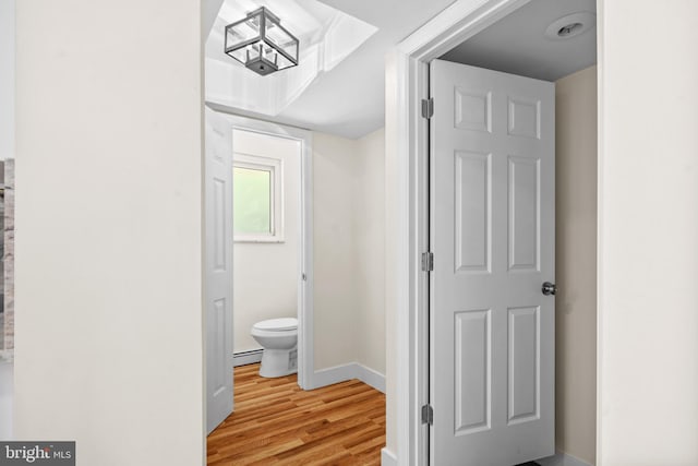 hallway with light hardwood / wood-style flooring and a baseboard heating unit