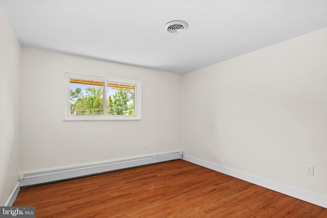 unfurnished room with hardwood / wood-style floors and a baseboard radiator