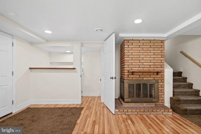 unfurnished living room with light hardwood / wood-style floors and a brick fireplace