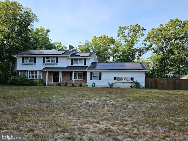 view of front of home with a front yard and solar panels