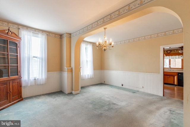 carpeted spare room featuring an inviting chandelier and sink