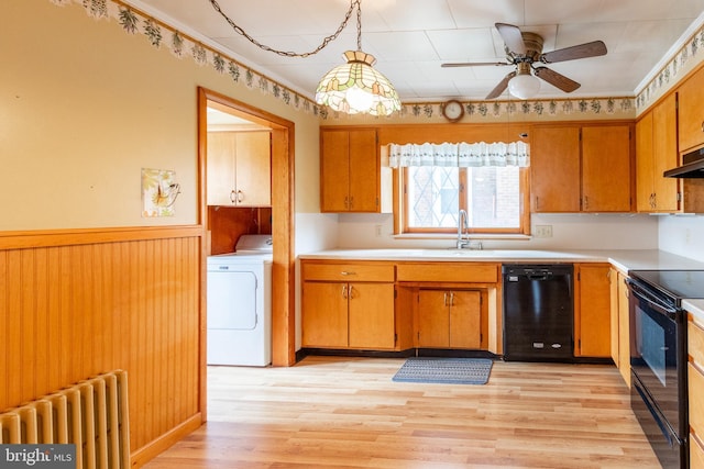 kitchen featuring radiator, sink, washer / clothes dryer, pendant lighting, and black appliances