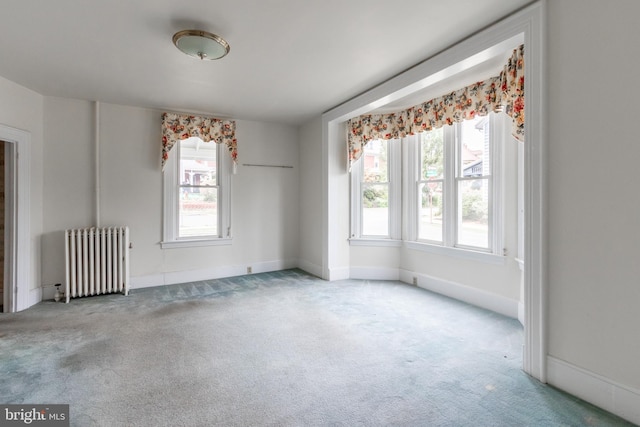 carpeted empty room with a wealth of natural light and radiator