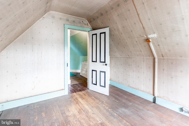 bonus room featuring lofted ceiling, dark wood-type flooring, and wood walls