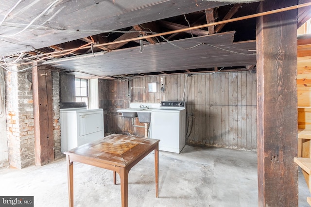 basement featuring sink, washing machine and dryer, and wood walls