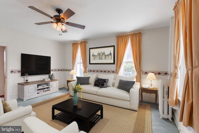 living room featuring ceiling fan, radiator heating unit, and light colored carpet