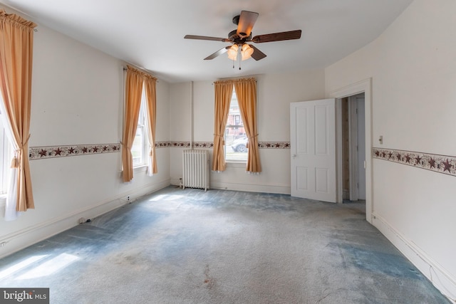 carpeted empty room with ceiling fan and radiator heating unit