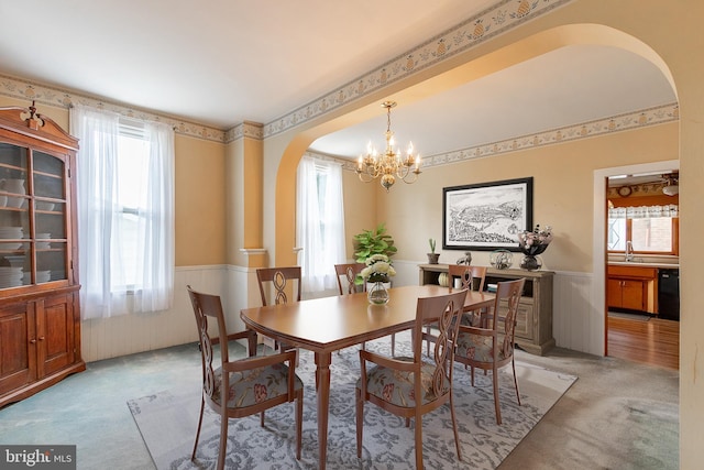 carpeted dining area with plenty of natural light, sink, and a chandelier