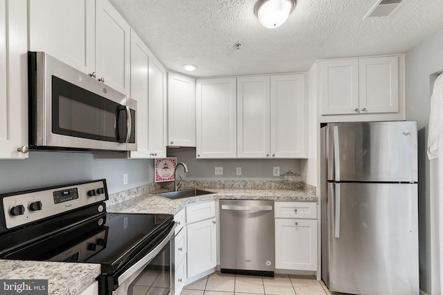 kitchen featuring white cabinetry, sink, light tile patterned floors, and appliances with stainless steel finishes