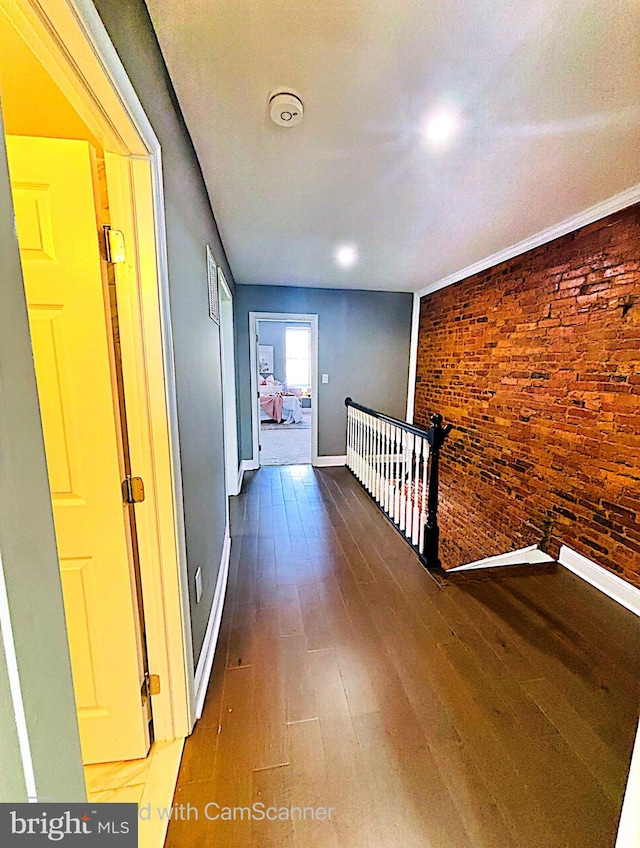 corridor featuring dark wood-type flooring and brick wall