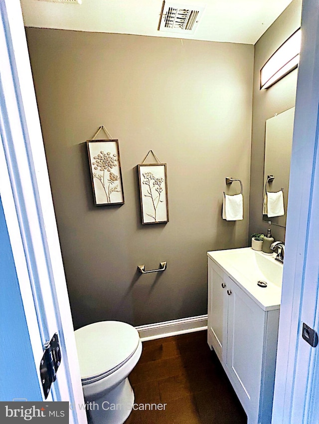 bathroom with hardwood / wood-style flooring, vanity, and toilet