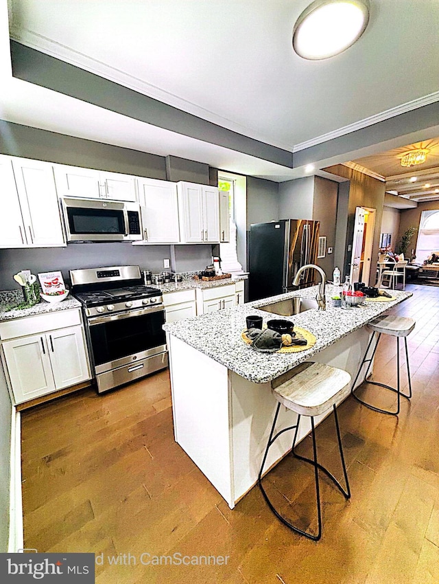 kitchen with a kitchen island with sink, stainless steel appliances, light hardwood / wood-style floors, and a breakfast bar