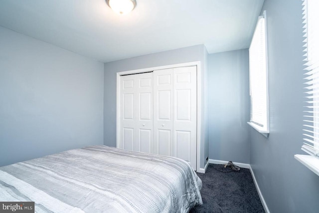 carpeted bedroom with a closet and baseboards