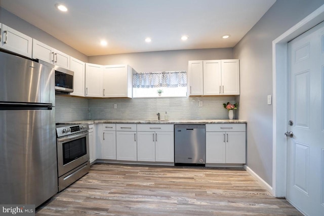 kitchen featuring appliances with stainless steel finishes, tasteful backsplash, white cabinets, and a sink