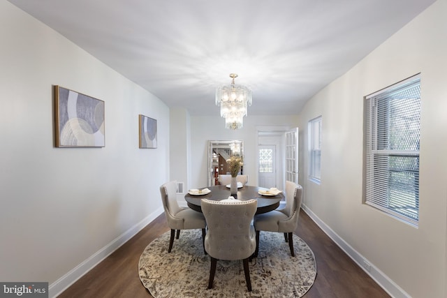 dining area with a notable chandelier and dark hardwood / wood-style flooring