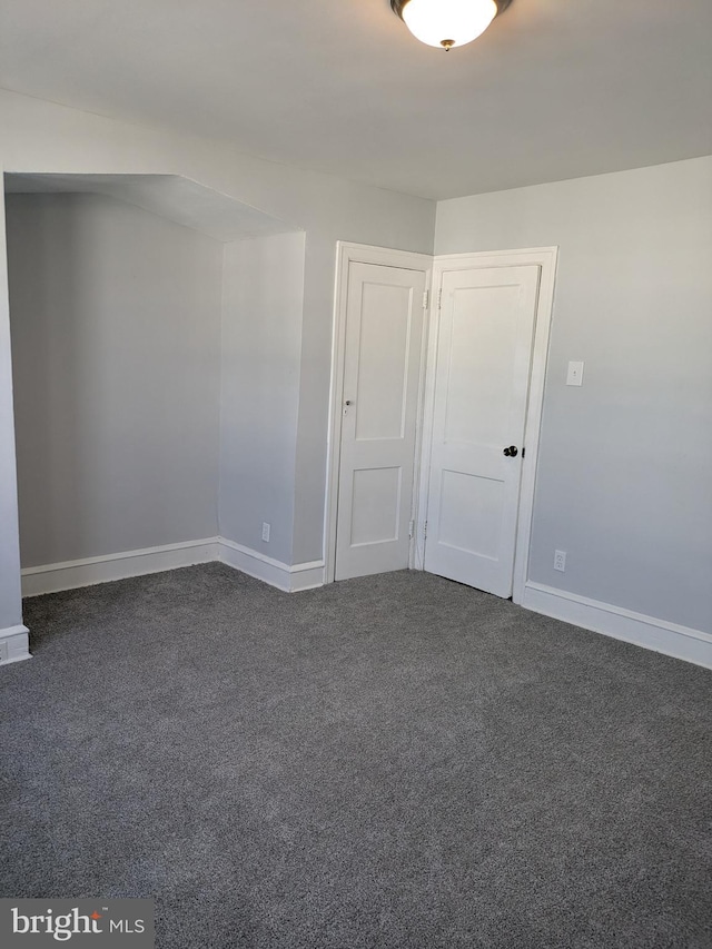 spare room with dark colored carpet