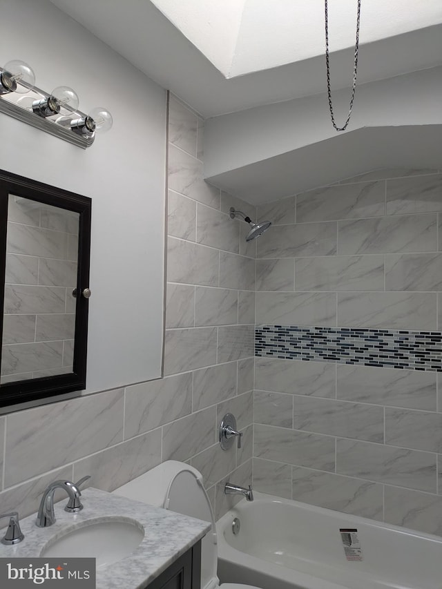 full bathroom featuring vanity, tiled shower / bath combo, and toilet