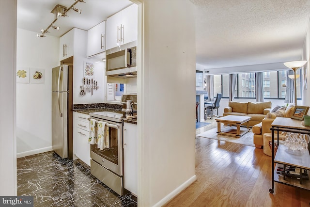 kitchen featuring white cabinets, appliances with stainless steel finishes, a textured ceiling, and dark wood-type flooring