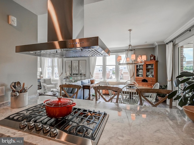 kitchen with ornamental molding, stainless steel gas stovetop, wall chimney exhaust hood, and a healthy amount of sunlight