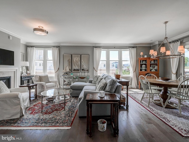 living room featuring a healthy amount of sunlight, dark wood-type flooring, a chandelier, and ornamental molding