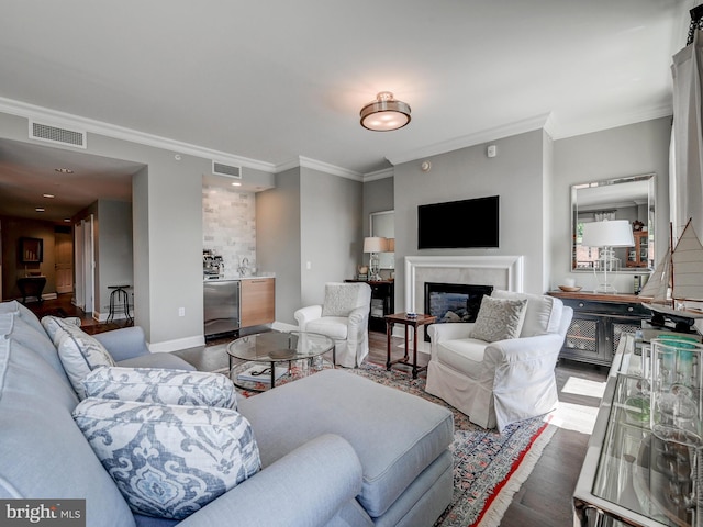 living room with a high end fireplace, crown molding, and dark wood-type flooring