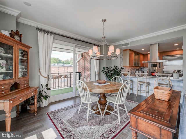 dining space with wood-type flooring, ornamental molding, and an inviting chandelier