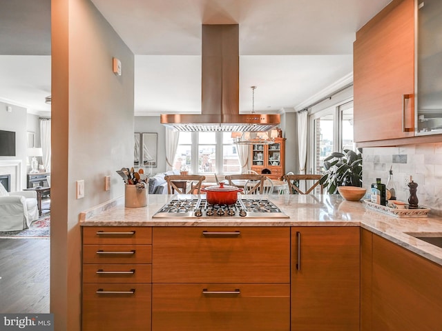 kitchen featuring island range hood, light stone countertops, kitchen peninsula, and stainless steel gas cooktop